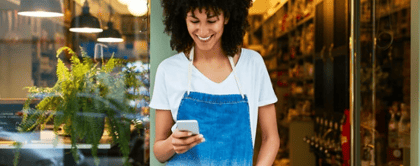 Vrouw kijkt op zakelijke telefoon voor haar winkel