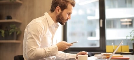 Man gebruikt AI op mobiel en laptop